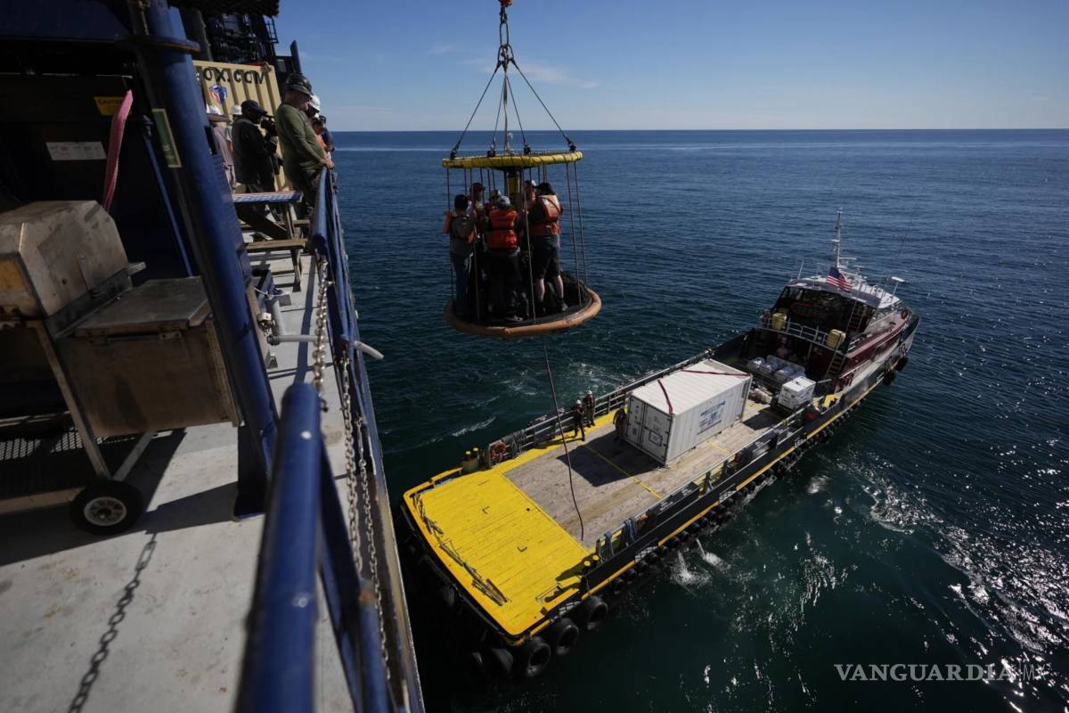 $!Los miembros de la Expedición 501 en una canasta Billy Pugh son bajados de la plataforma del barco elevador Robert al Gaspee.