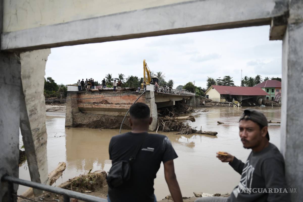 $!Hombres sentados cerca de un puente que se derrumbó durante una inundación repentina en Pidie Jaya, provincia de Aceh, Indonesia.