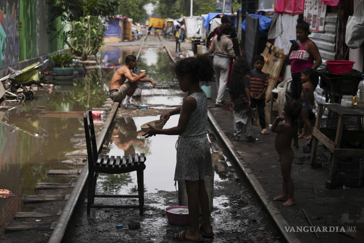 $!Un joven migrante lava un plato después de un aguacero en un campamento instalado a lo largo de las vías del tren Vallejo en Ciudad de México.