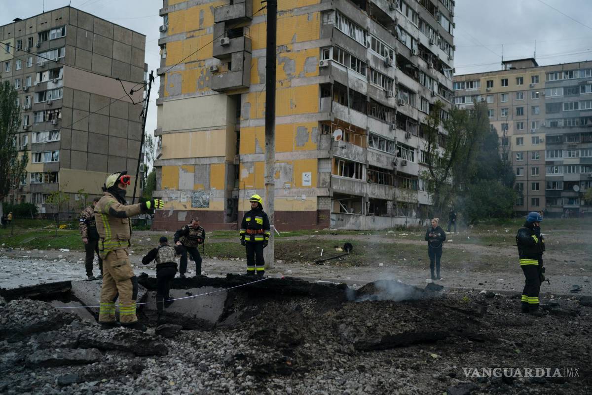 $!Bomberos y policías trabajan en un sitio donde una explosión creó un cráter en la calle después de un ataque ruso en Dnipro, Ucrania.
