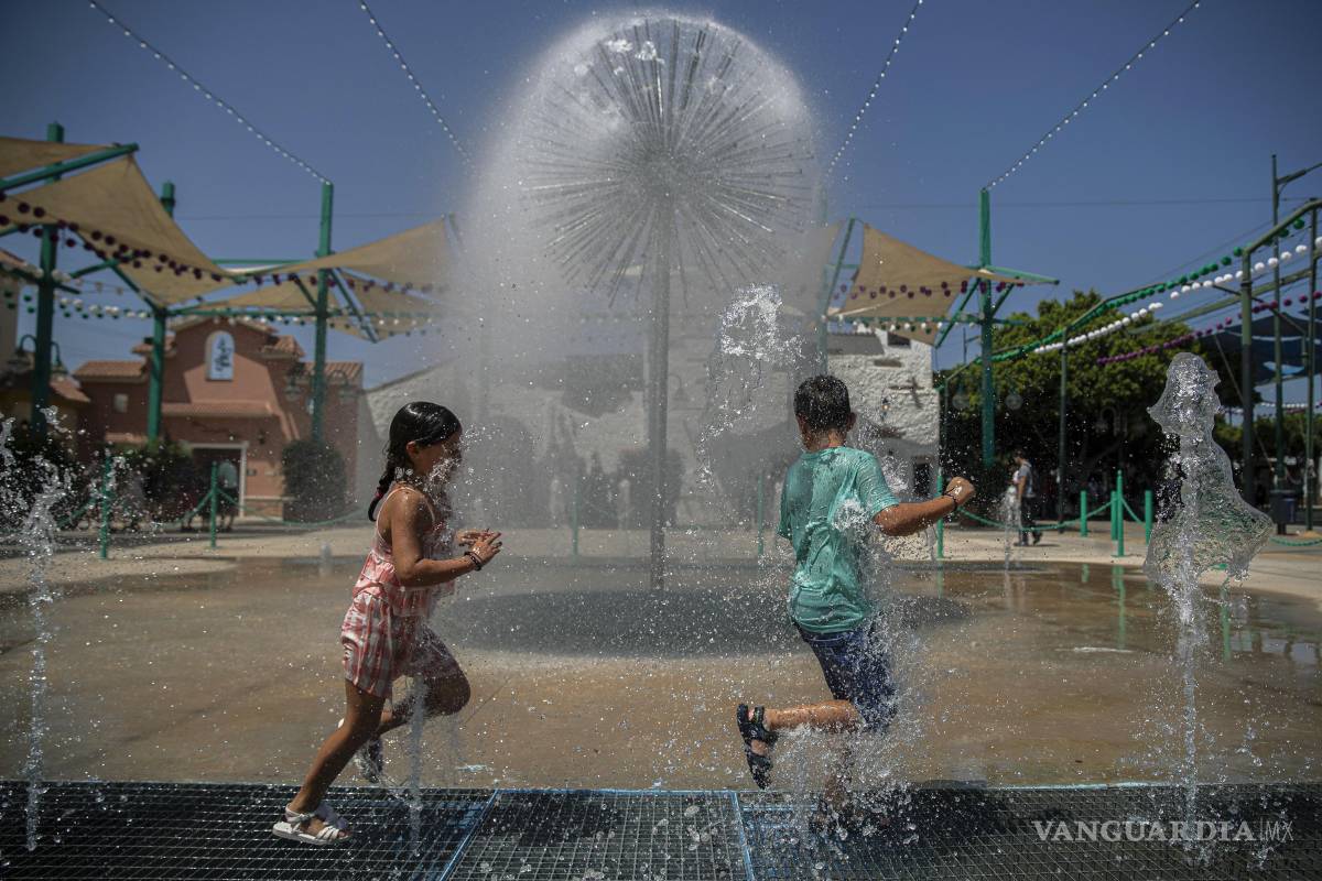 $!Dos niños dejan sus pantallas y móviles para jugar al aire libre con los chorros de agua en el real del Cortijo de Torres en la Feria de Málaga.