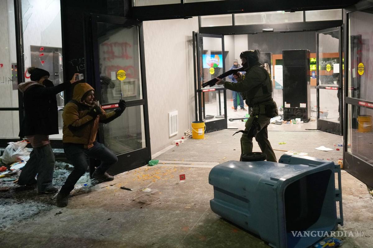 $!Un agente federal apunta con un arma a una persona afuera de un hotel durante una protesta en Minneapolis el domingo 25 de enero de 2026.