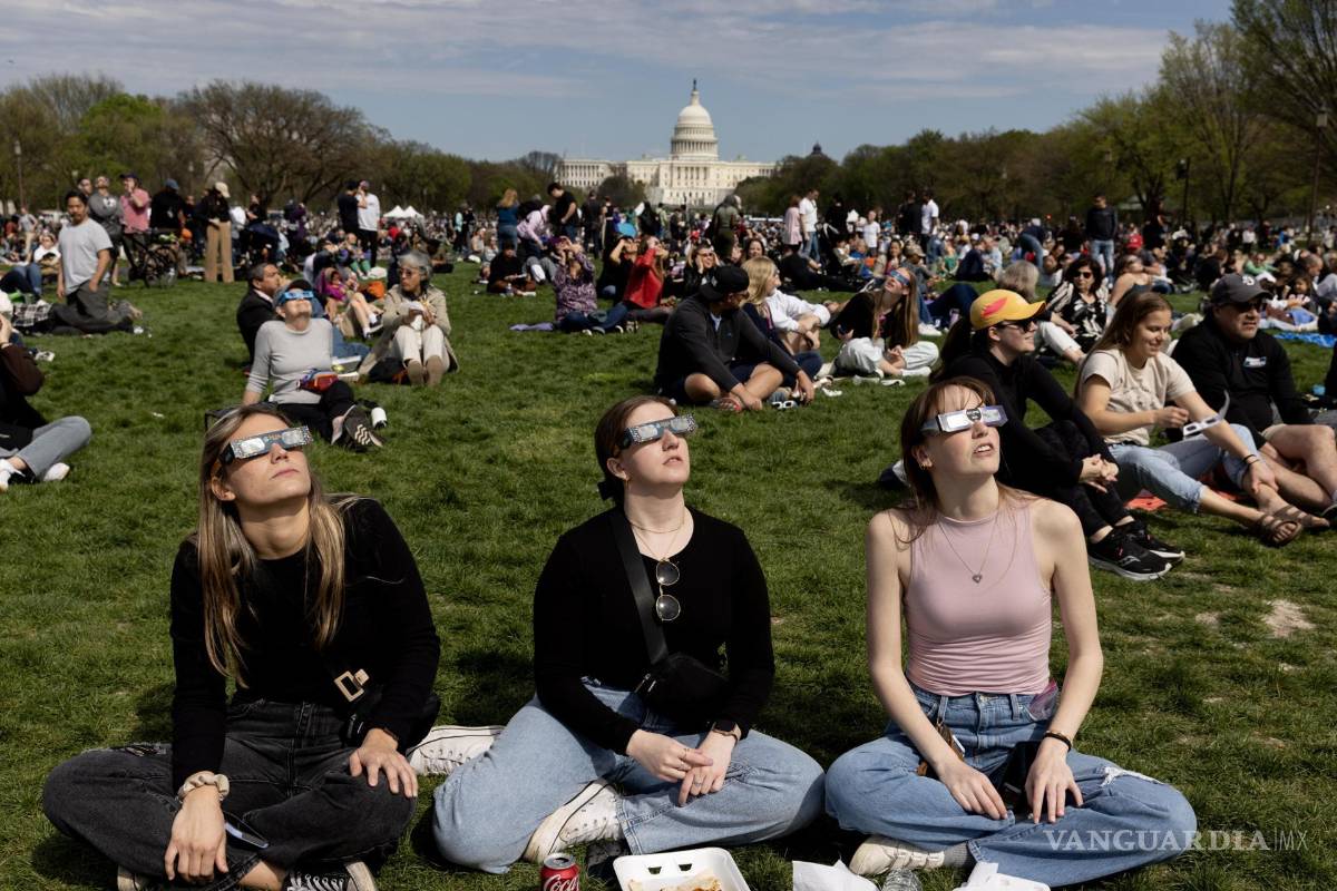 $!La gente en el National Mall observa un eclipse solar parcial, con el edificio del Capitolio de los Estados Unidos visto detrás, en Washington, DC.