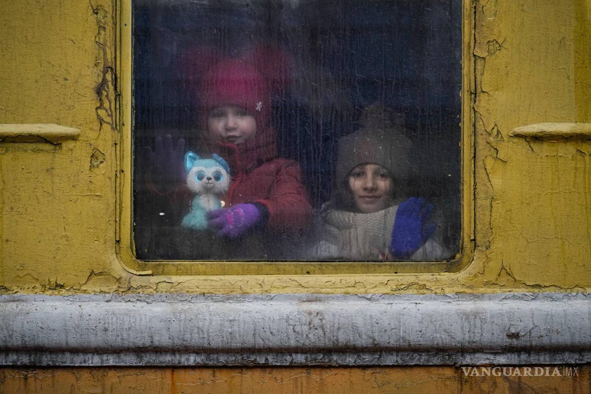$!Niños mirando por la ventana de un tren sin calefacción con destino a Leópolis, en Kiev, Ucrania, el jueves 3 de mazo de 2022.