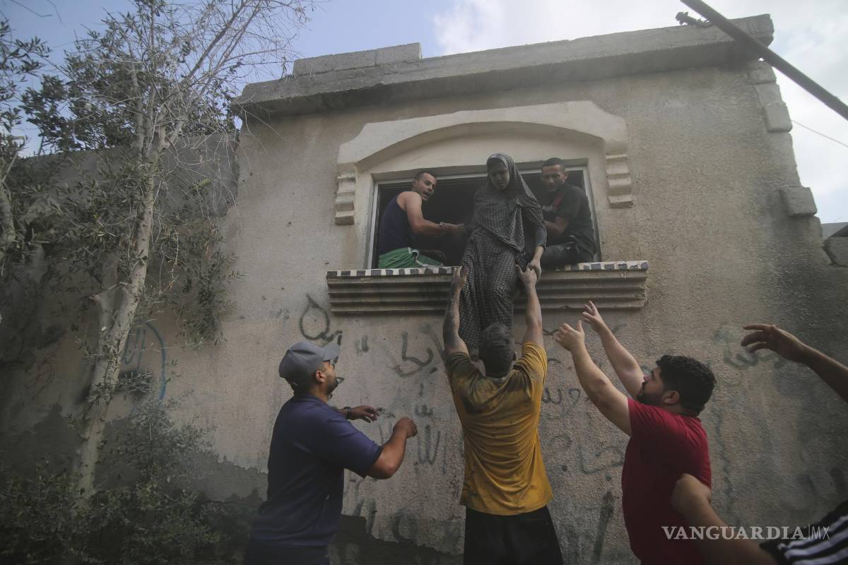 $!Palestinos desalojan un edificio alcanzado por un bombardeo aéreo israelí sobre la Franja de Gaza, en Rafah, el 22 de octubre de 2023.