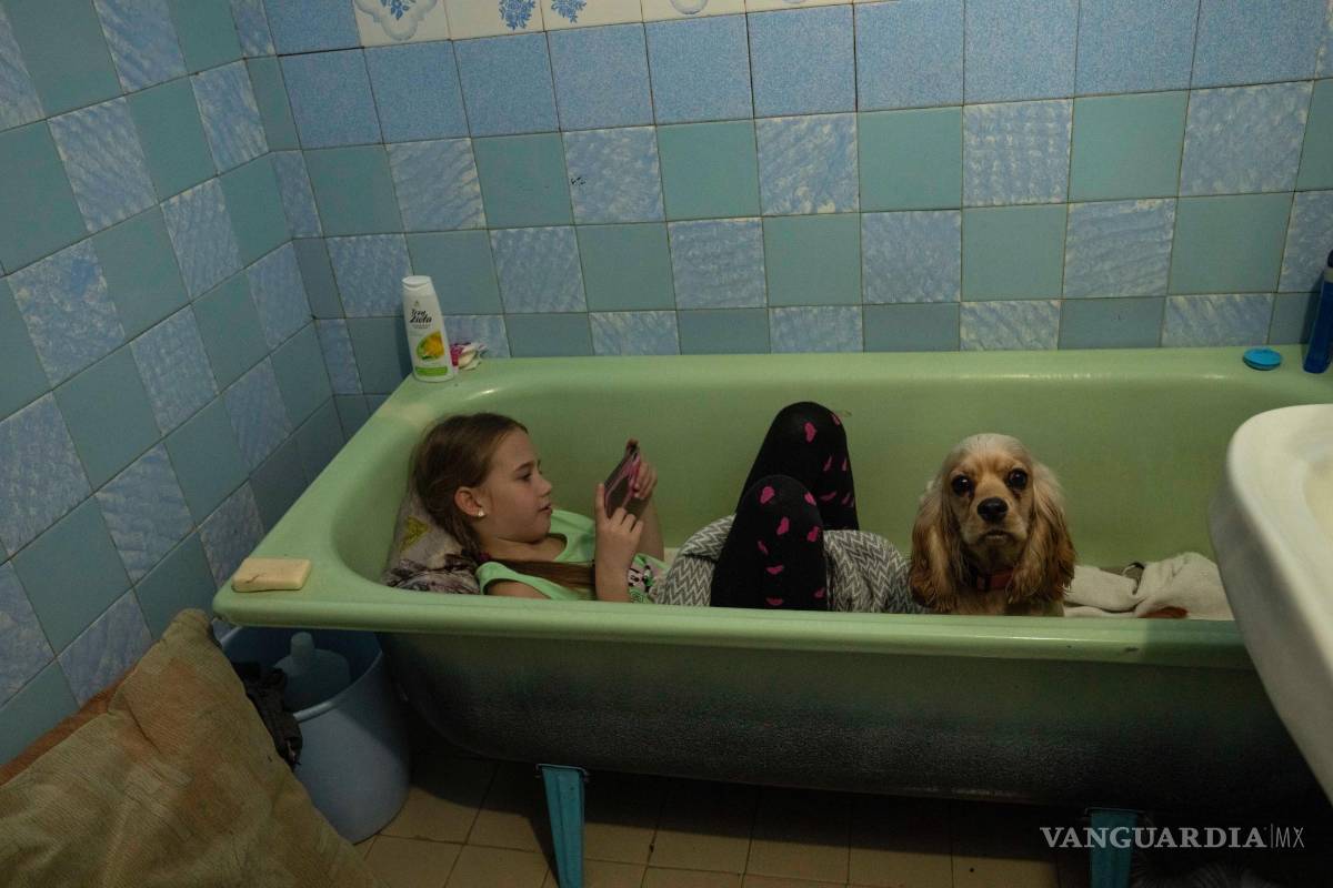 $!Zlata-Maria Shlapak se sienta con su cachorro Letti en la bañera al sonar una sirena antiaérea, en el apartamento que renta su familia en Leópolis.