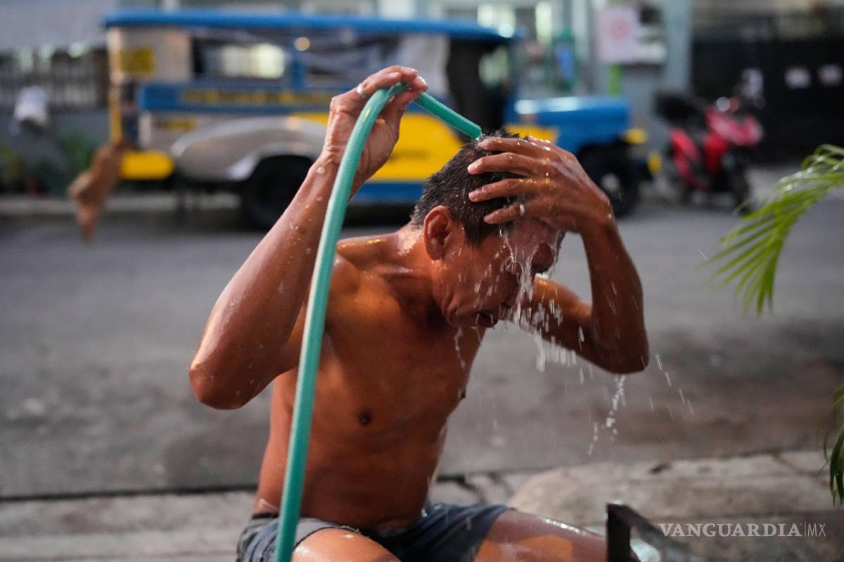 $!El conductor de Jeepney Edgar Funelas se lava en una calle junto al jeepney donde viven él y su hija de 10 años en Quezon City, Filipinas, el viernes 10 de abril de 2026.