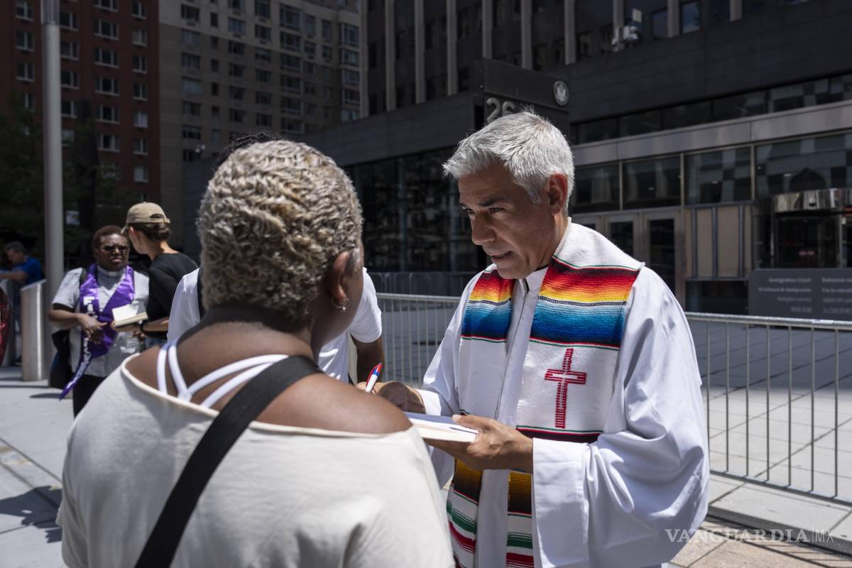 $!El padre Fabián Arias, a la derecha, asiste a una familia inmigrante frente al edificio federal Jacob K. Javits en Nueva York.