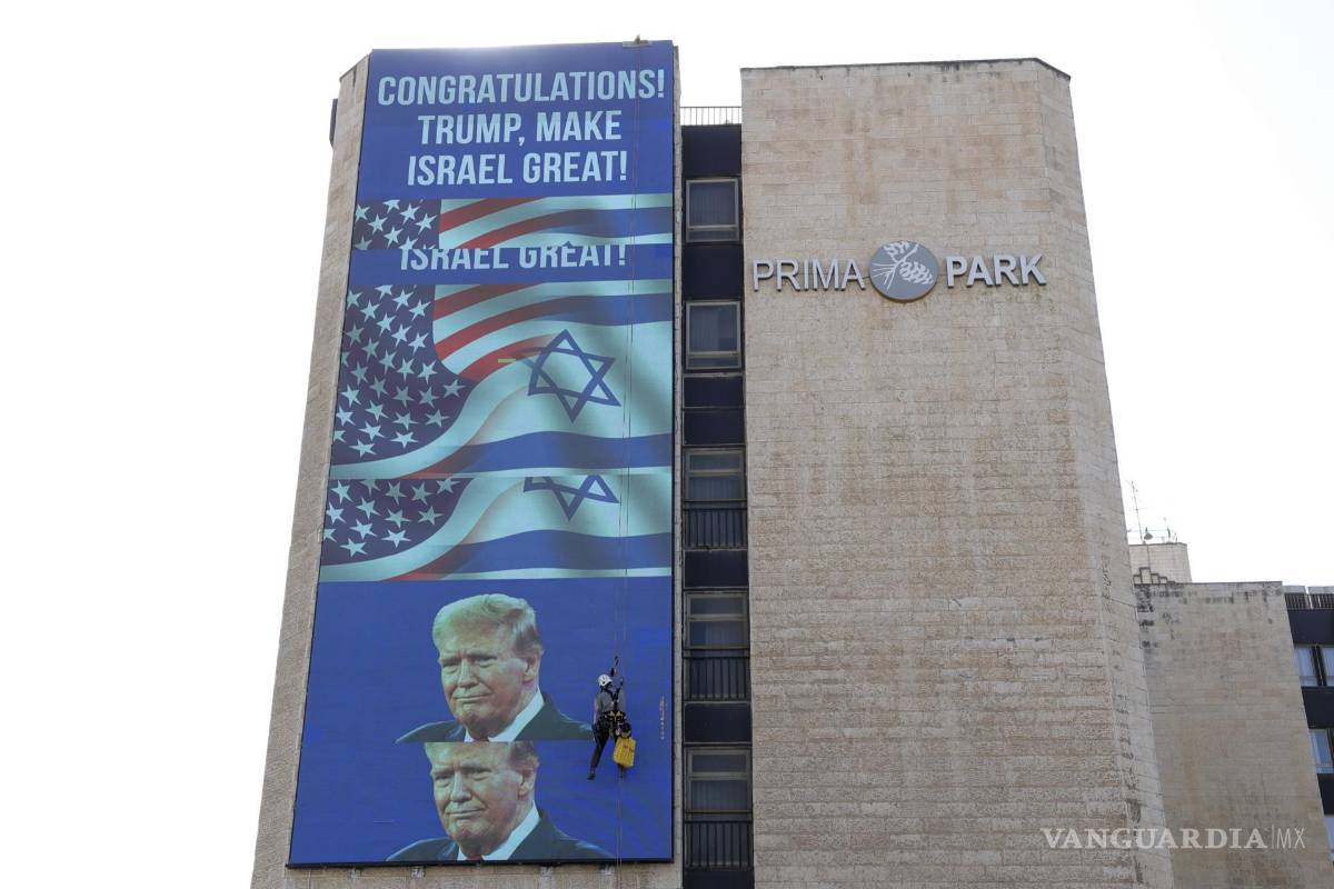 $!Un trabajador colgado en un edificio en el que se exhibe un gran cartel de felicitación a Donald Trump, a la entrada de Jerusalén.