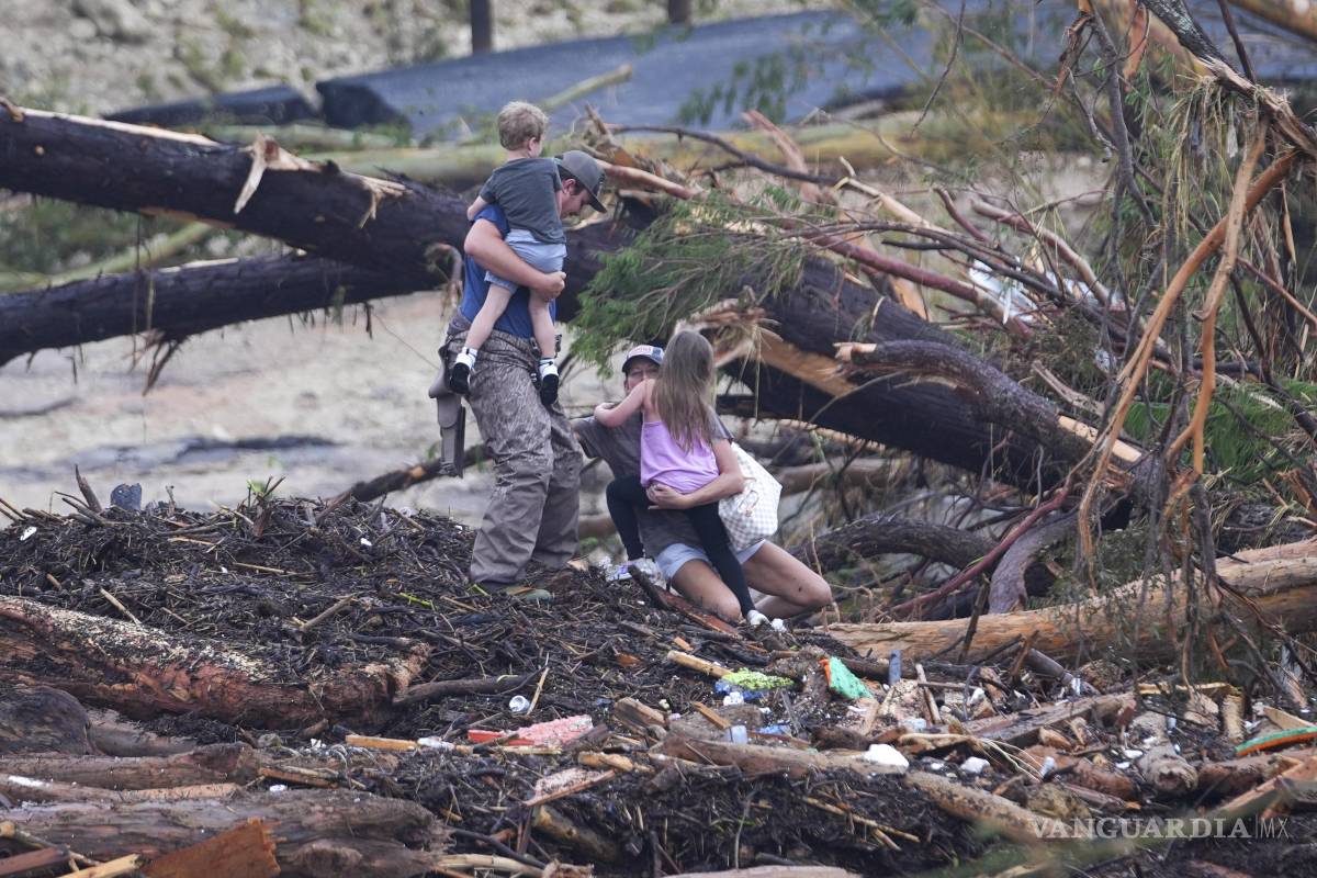 $!Una mujer se cae mientras camina entre escombros en un puente sobre el río Guadalupe luego de que una inundación repentina azotó la zona en Ingram, Texas.