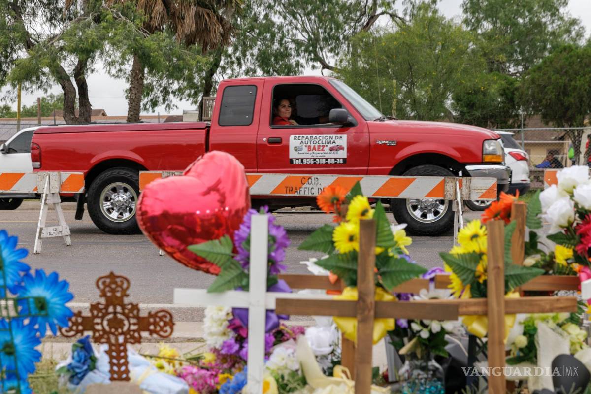 $!Un pasajero en una camioneta mira un sitio conmemorativo donde ocho migrantes murieron mientras esperaban en una parada de autobús en Brownsville, Texas.