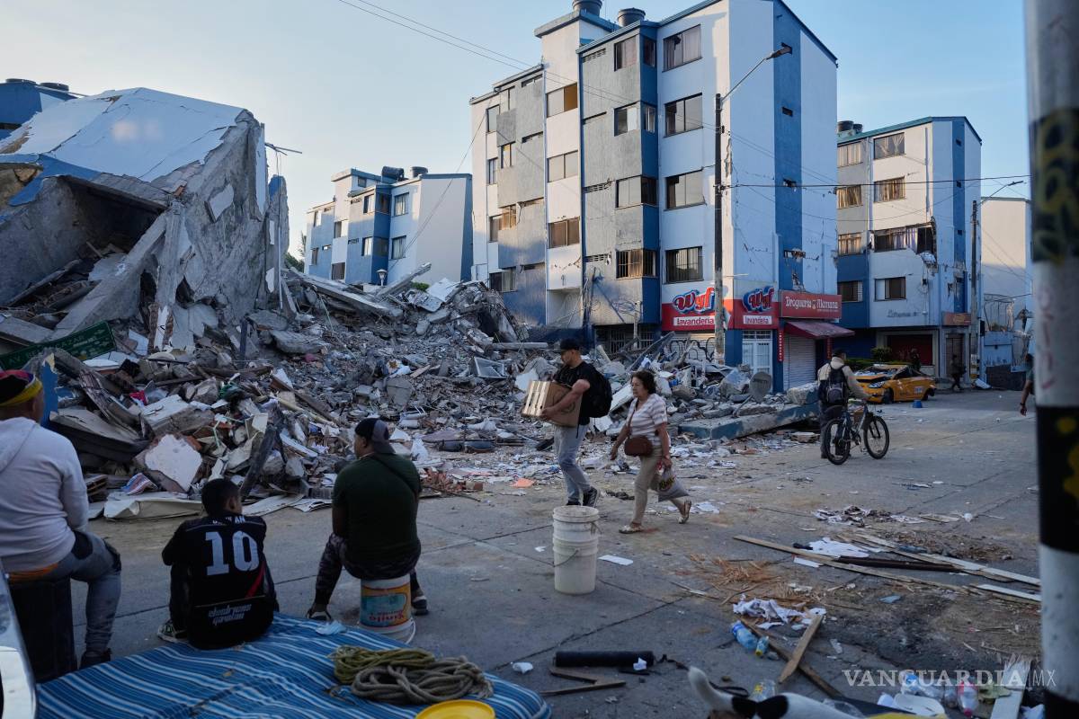 $!Varias personas pasan junto a un edificio derrumbado al día siguiente del terremoto que azotó Pereira, Colombia.