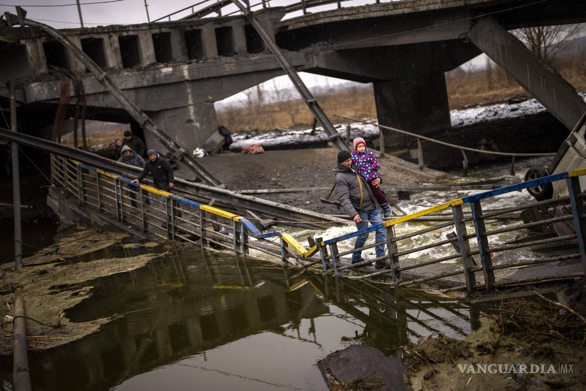 $!La combatiente Valery, de 37 años, carga a un niño mientras ayuda a una familia a cruzar un puente que fue destruido por artillería, el miércoles 2 de marzo de 2022, en Kiev. (AP Foto/Emilio Morenatti)