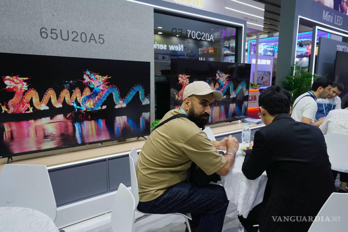 $!Visitantes se sientan cerca de televisores fabricados por Guangzhou HD Electronics Technology Co. Ltd., exhibidos en la Feria de Cantón en Guangzhou, China.