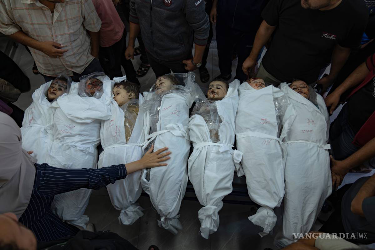 $!Gente de pie en torno a cuerpos de niños muertos en un bombardeo israelí en la Franja de Gaza, en una morgue en Jan Yunis, el jueves 19 de octubre de 2023.