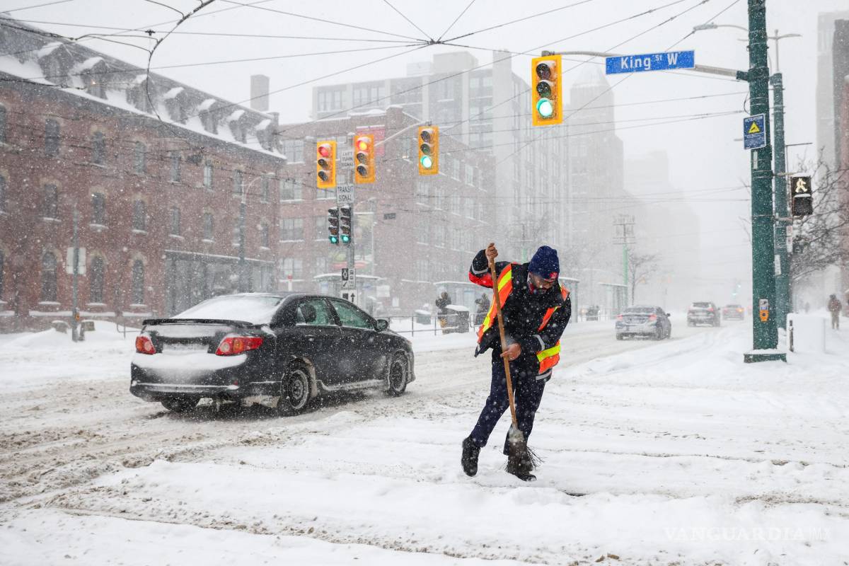 $!Un empleado de la TTC limpia las vías del tranvía con una escoba en Toronto, mientras una tormenta invernal azota la región.