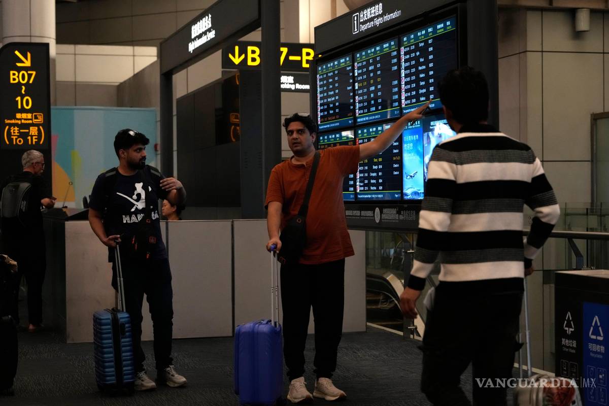 $!Extranjeros observan un panel informativo sobre vuelos en el aeropuerto de Baiyun, en Guangzhou, provincia de Guangdong, al sur de China.