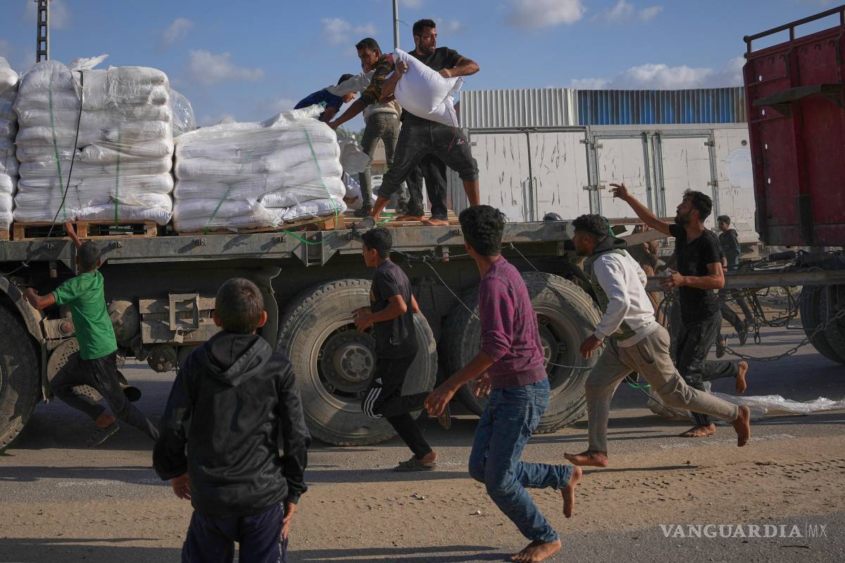 $!Palestinos recogen sacos de harina de un camión en movimiento que transporta ayuda del PMA en Deir al-Balah, en el centro de Gaza, el 15 de noviembre de 2025.