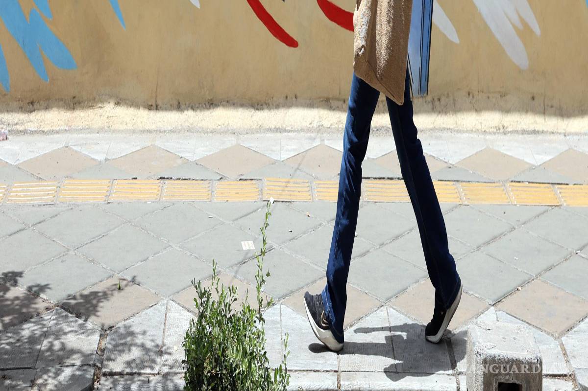 $!Una mujer iraní camina junto a un mural antiestadounidense y antiisraelí en una calle de Teherán, Irán, el 8 de mayo de 2026.