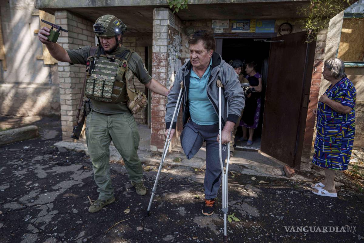 $!Un agente de policía ayuda a Mykhailo Maistruk, de 67 años, durante la evacuación de Kostiantynivka, Ucrania.
