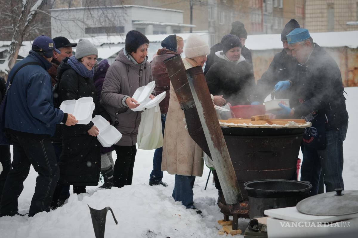 $!El voluntario Marat Darmenov (d) sirve comida caliente gratuita a los residentes de Kiev durante un apagón provocado por los frecuentes ataques aéreos rusos.