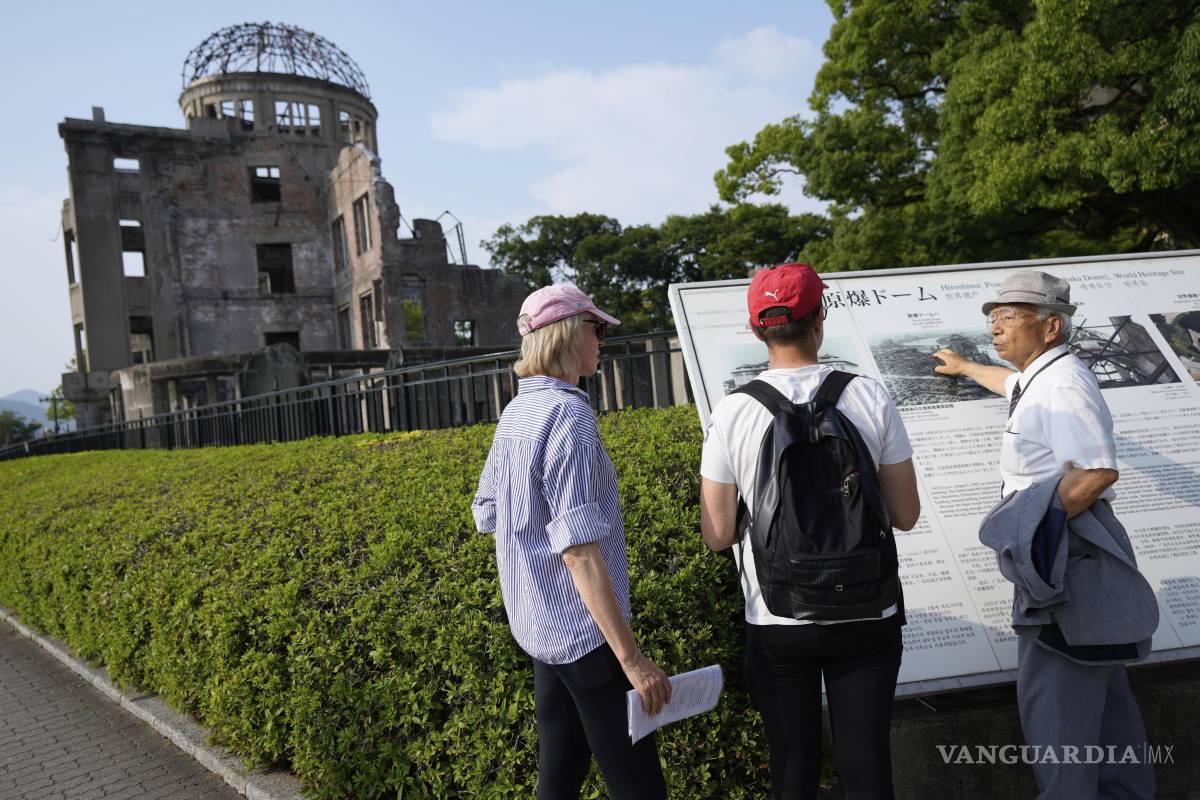 $!Kunihio Iida, sobreviviente de la bomba atómica y guía voluntario habla en inglés a visitantes extranjeros frente a la Cúpula de la Bomba Atómica en Hiroshima.