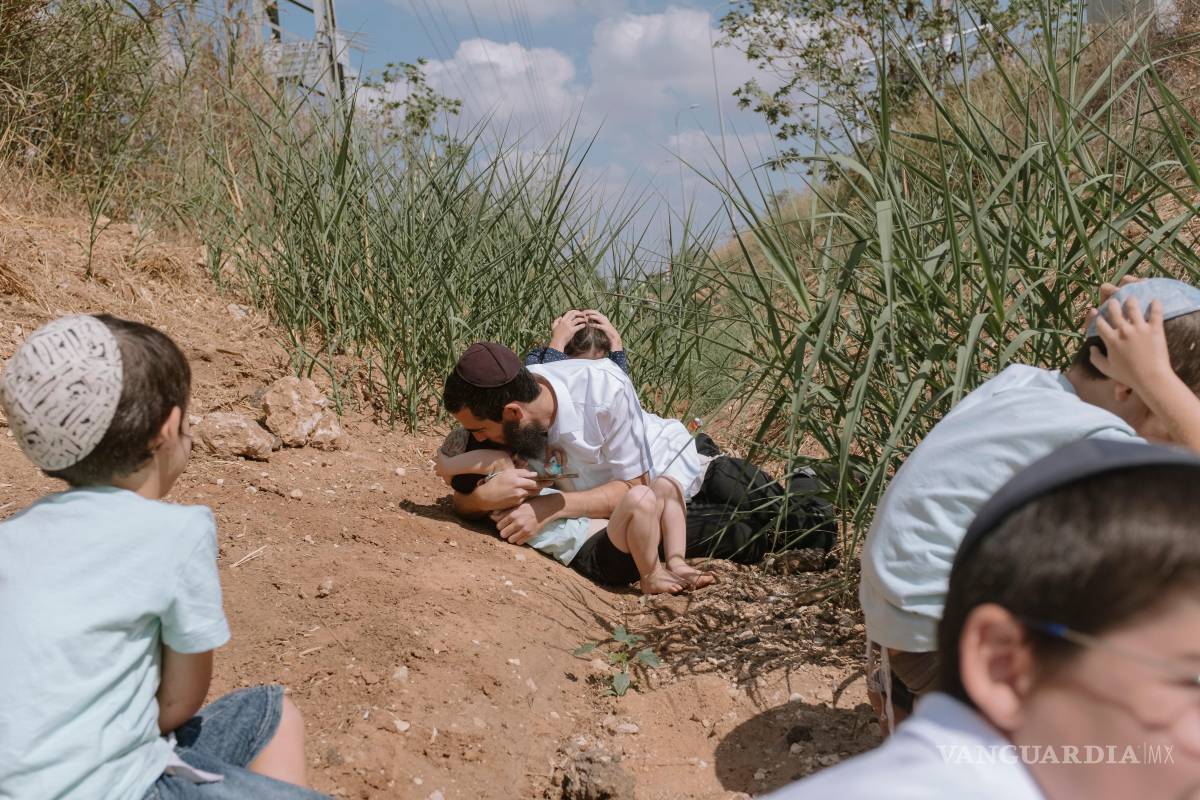 $!Gente se cubre mientras suena una sirena antiaérea para alertar de cohetes lanzados en la Franja de Gaza en Rehovot, Israel, el viernes 13 de octubre de 2023.