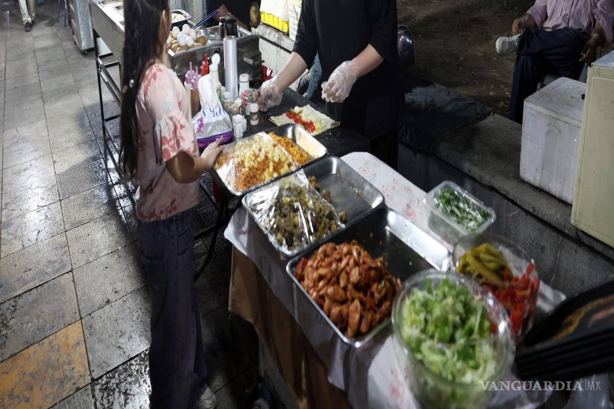 $!Una mujer iraní prepara comida callejera en un puesto de mercado en el centro de Teherán, Irán, el 26 de agosto de 2026.
