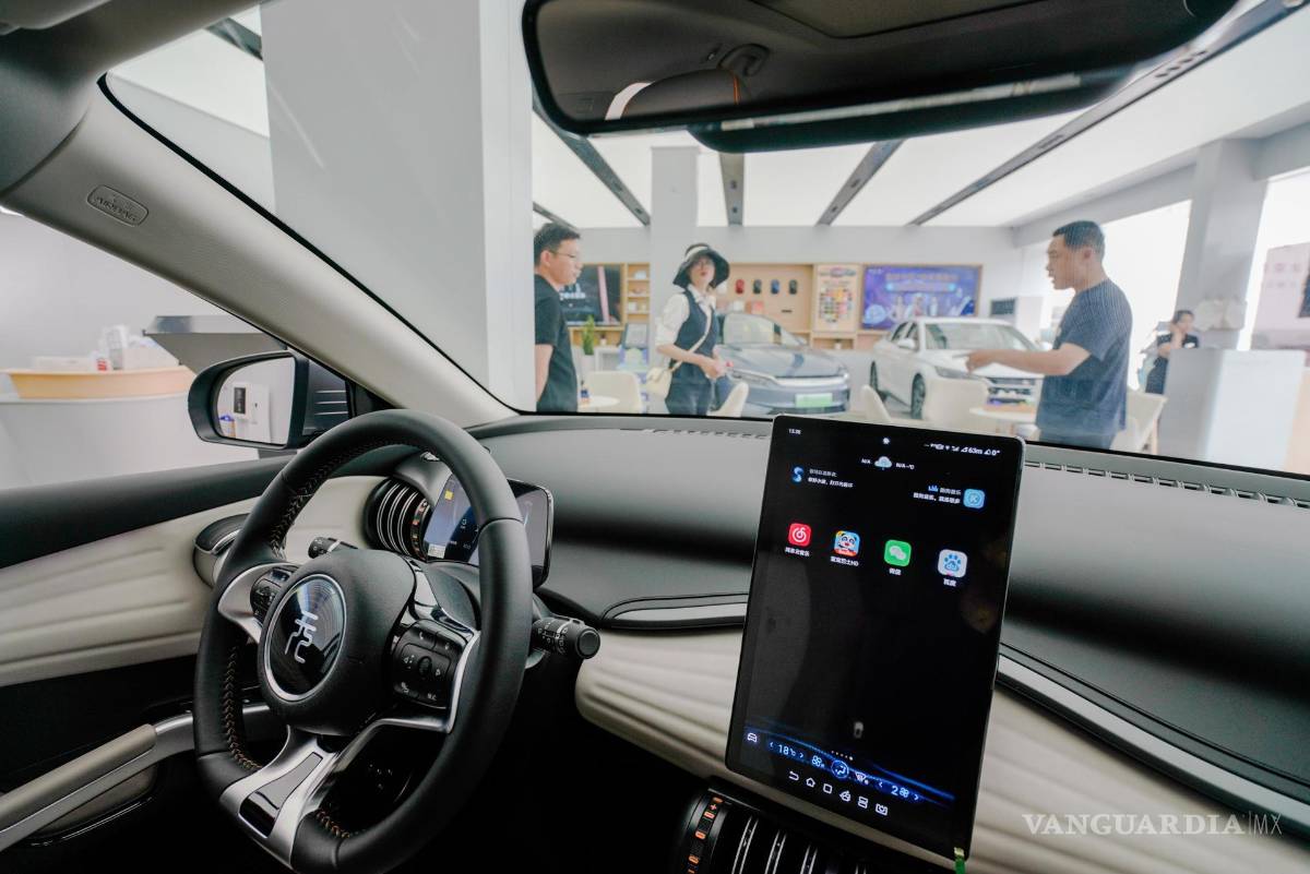 $!La gente mira un automóvil eléctrico BYD en una sala de exposición de BYD en Beijing, China.