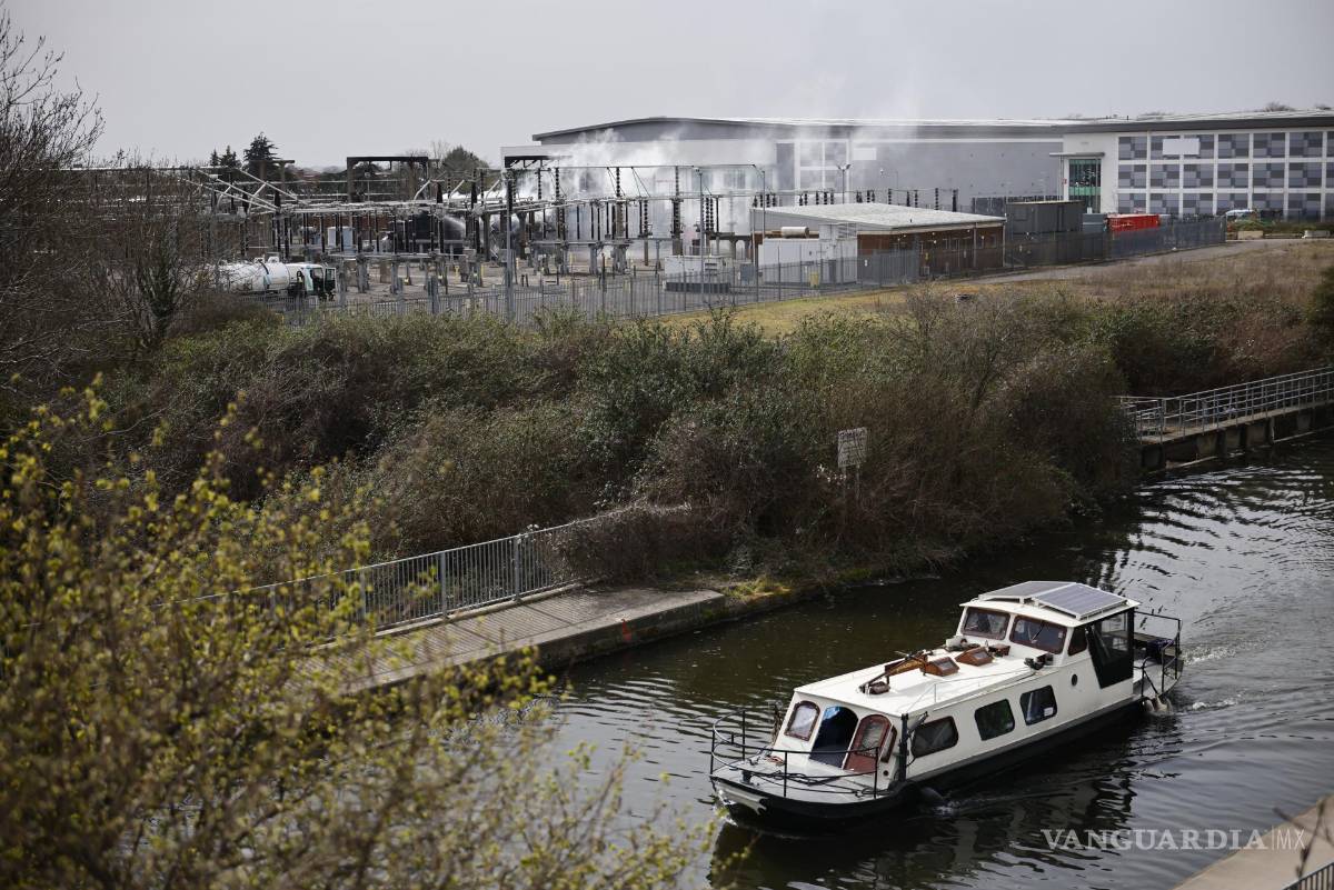 $!Un barco pasa por el canal mientras el humo se eleva desde la subestación eléctrica de North Hyde que se incendió en Londres, Gran Bretaña.