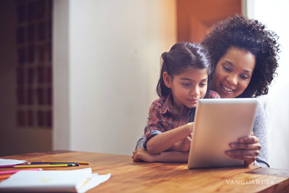 $!Madre e hija utilizando una tableta electrónica en el salón de su casa.
