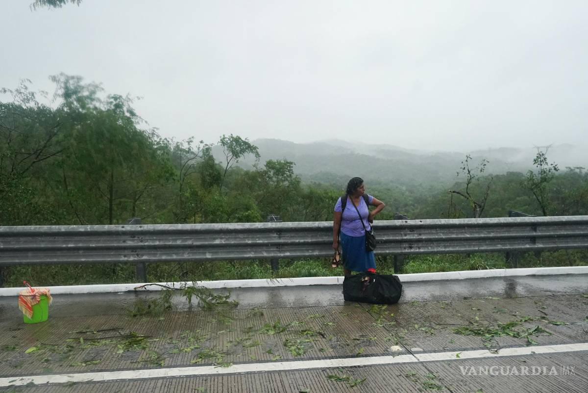 $!Una mujer que se bajó de un autobús parado en una carretera bloqueada por un deslizamiento de tierra provocado por el huracán Otis cerca de Acapulco, México.
