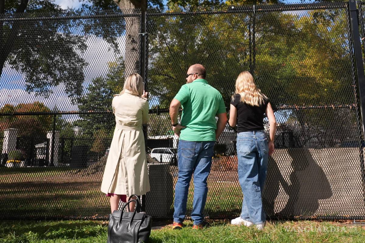 $!Personas observa desde el exterior de una valla de seguridad mientras continúa la demolición en el Ala Este de la Casa Blanca en Washington.
