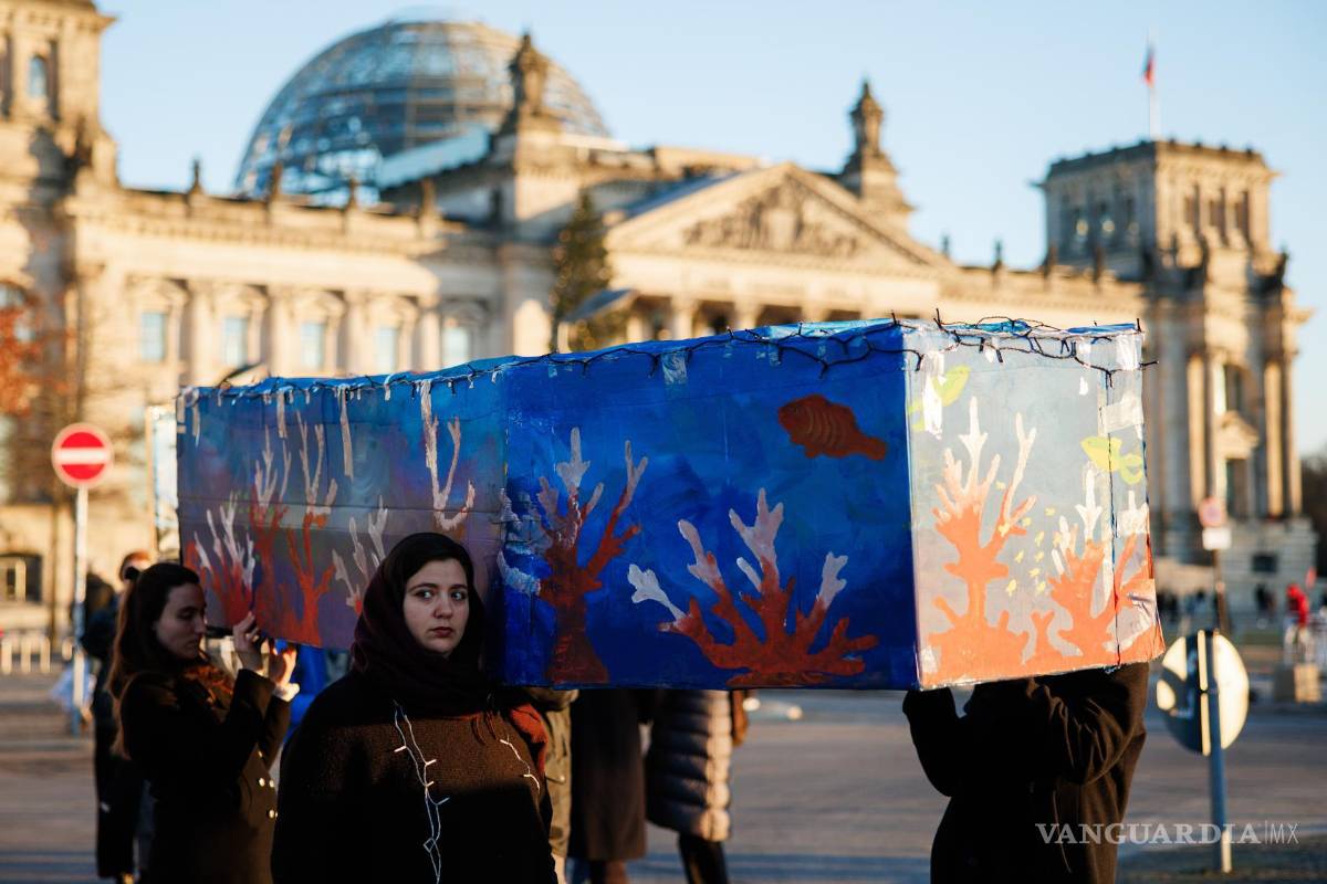 $!Activistas de Extinction Rebellion cargan un ataúd gigante frente al Parlamento alemán con motivo de los 10 años del Acuerdo de París en Berlín.