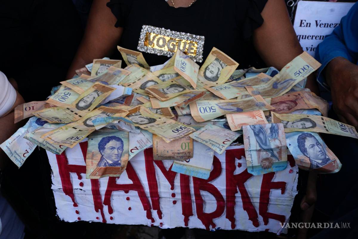 $!Un manifestante lleva una caja con la palabra hambre y billetes de bolívares, en una protesta para reclamar mayores salarios y beneficios en Caracas, Venezuela.