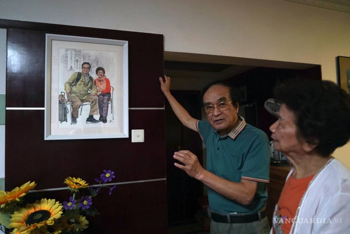 $!Zeng Fanzhi, un arquitecto jubilado convertido en artista, habla sobre una pintura de él con su esposa, Zhao Sirong, en su apartamento en Shenzhen en China.