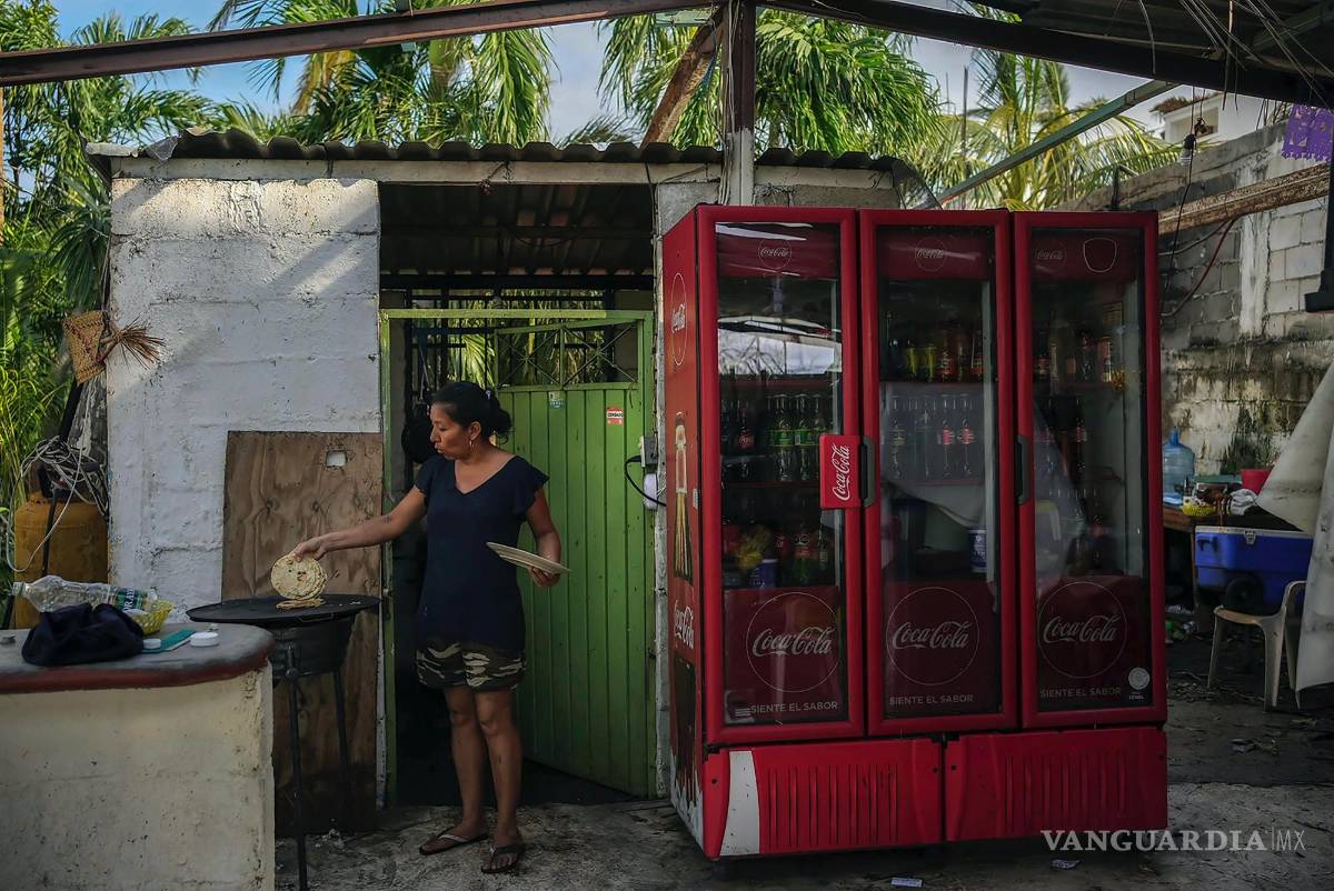 $!Natividad Reynoso cocina tortillas para su familia después del huracán Otis que arrancó parte del techo de su casa en Acapulco, México.