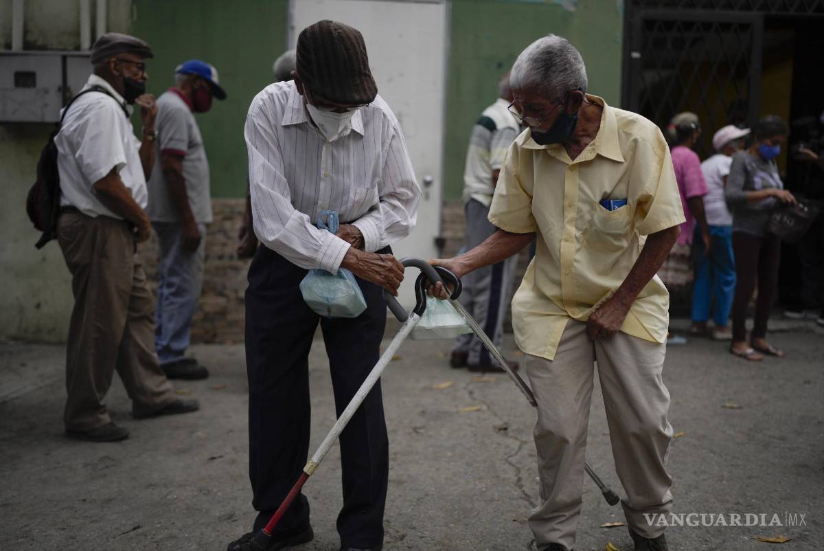 $!Hombres golpean sus bastones para despedirse después de recibir sus comidas donadas en un comedor de beneficencia en el barrio de La Vega de Caracas, Venezuela, el 11 de marzo de 2022.