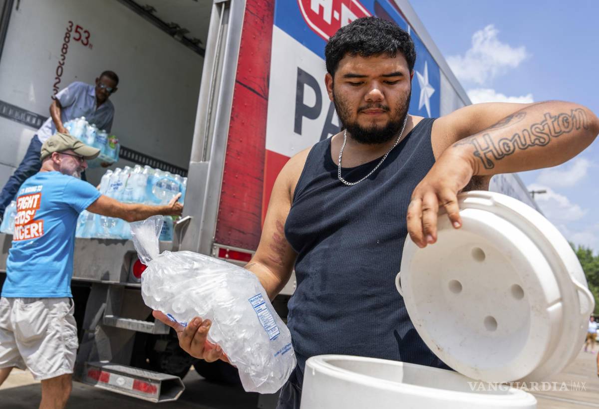 $!Daniel Valdez coloca una bolsa de hielo en una hielera mientras los voluntarios de Memorial Assistance Ministries distribuyen agua y hielo en Houston.