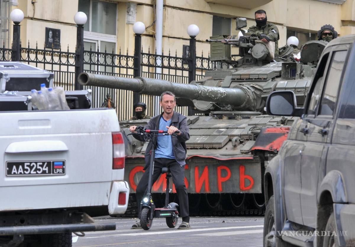 $!Un hombre monta un scooter junto a los militares de la compañía militar privada (PMC) Wagner Group en un tanque que dice ‘Siberia’ en Rostov-on-Don, Rusia.
