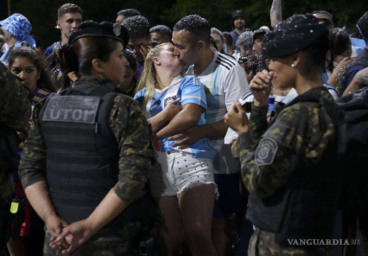 $!Una pareja se besan mientras esperan la llegada de la selección argentina de fútbol que ganó la Copa del Mundo fuera del campo de entrenamiento de la AFA.