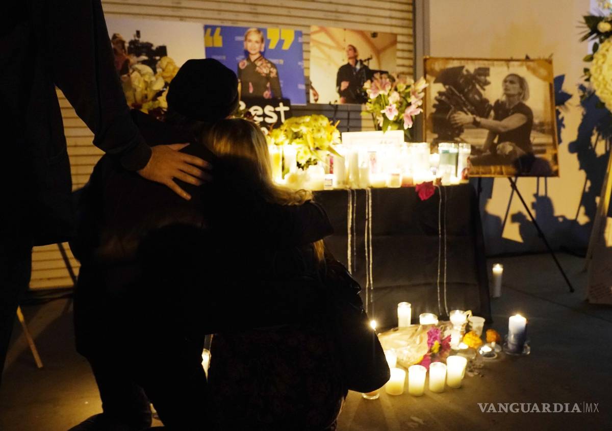 $!Asistentes se abrazan en una vigilia por la fallecida directora de fotografía Halyna Hutchins, representada en fotografías al fondo, el domingo 24 de octubre de 2021, en Burbank, California.