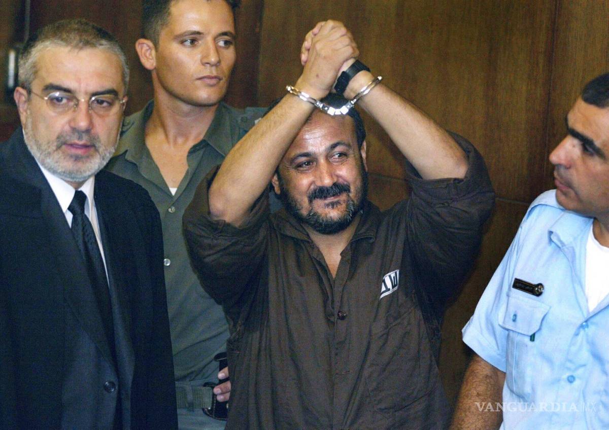 $!Marwan Barghouti, en el centro, levanta sus manos esposadas en el aire el primer día de su juicio en Tel Aviv, Israel, el 14 de agosto de 2002.
