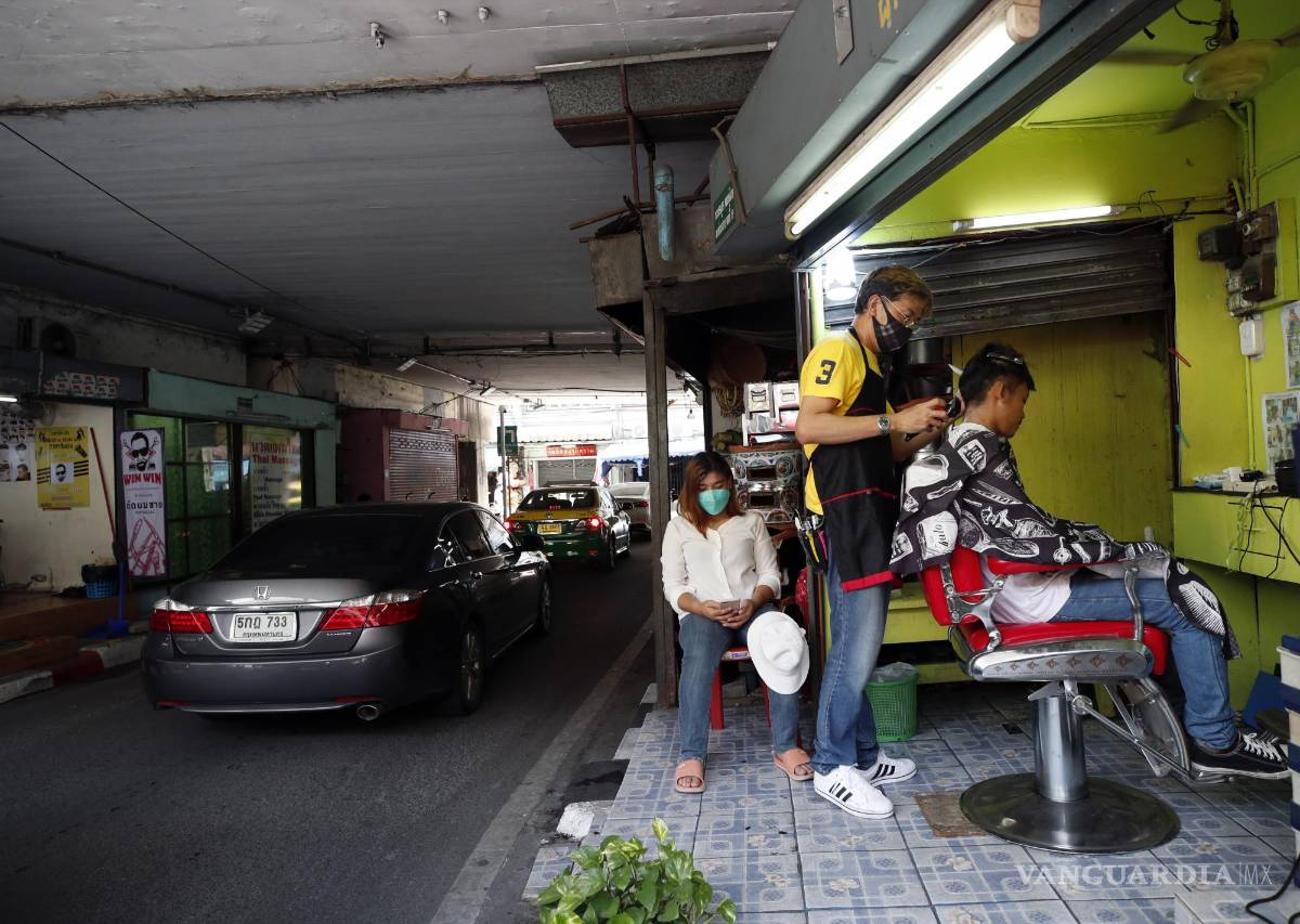 $!Un barbero tailandés corta el cabello de un cliente en una barbería al borde de la carretera en Bangkok, Tailandia.