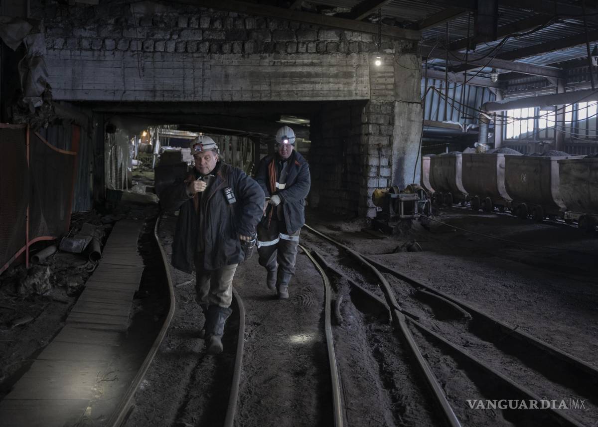 $!Trabajadores pasan junto a carros mineros llenos de carbón en una mina de Barentsburg, en Svalbard al oeste del norte de Groenlandia.