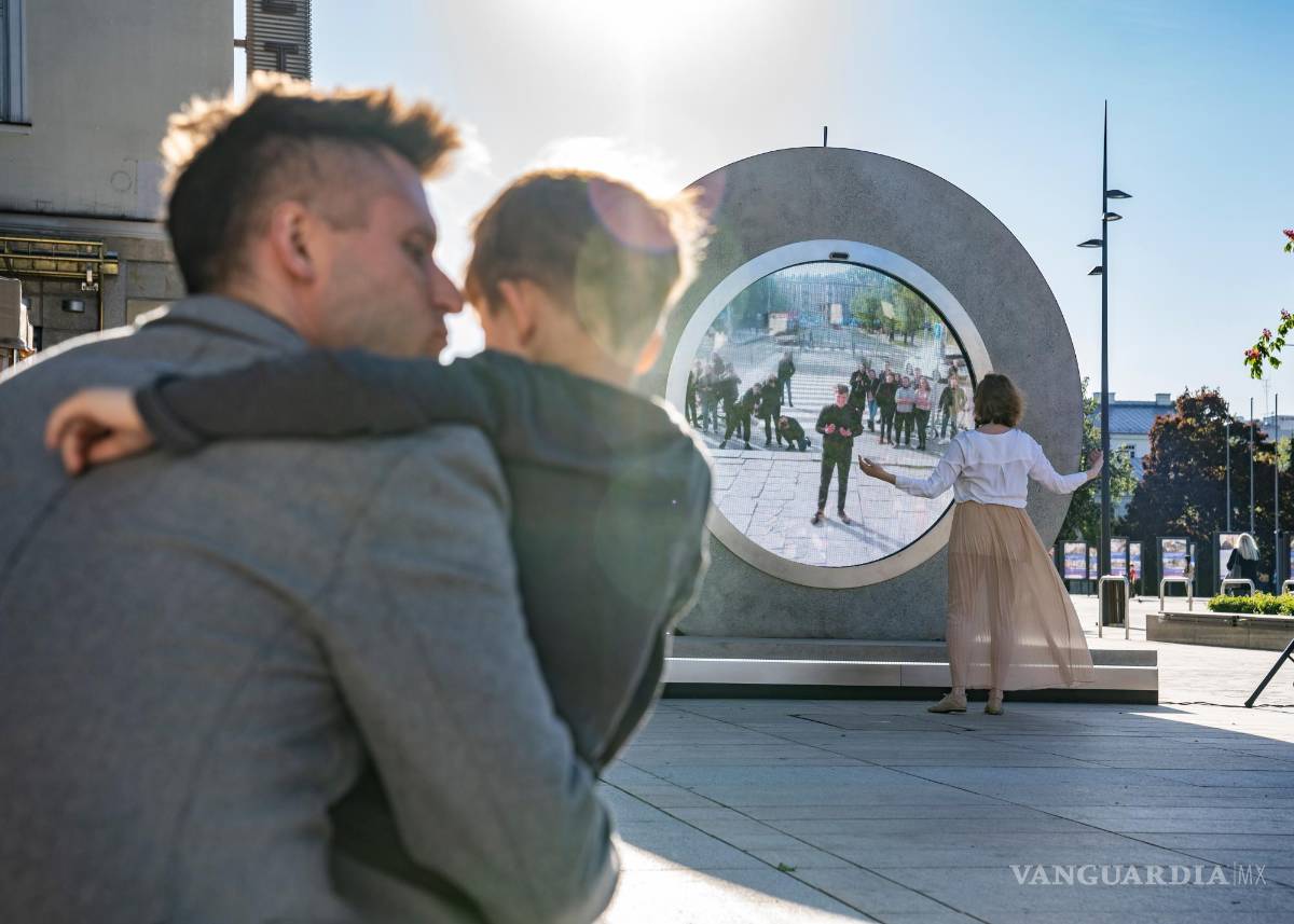$!Un padre con su hijo observa a una joven que se detiene a saludar ante la terminal de 'pOrtal' en Vilna, Lituani. EFE/Benediktas Gylys Foundation/Vilnius Gediminas Technical University