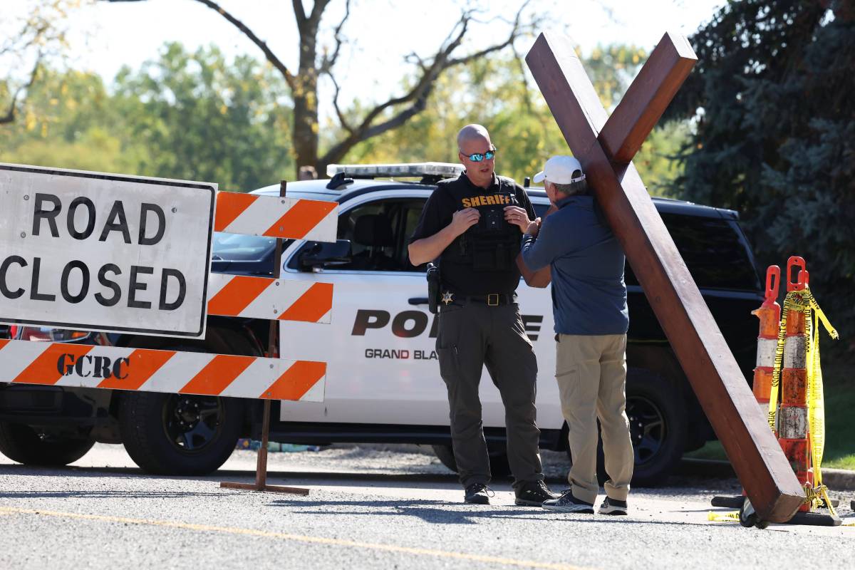 $!Dan Beazley, con su cruz de 3 metros, es detenido por un agente del sheriff cerca de la Iglesia de Jesucristo de los Santos de los Últimos Días en Grand Blanc, Michigan.