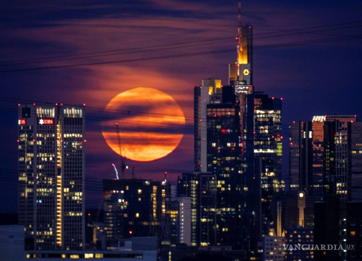 $!La luna llena se eleva detrás de los edificios en el distrito bancario de Frankfurt, Alemania. Durante un fenómeno conocido como la “ Strawberry Moon”.