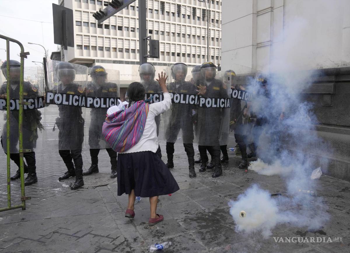 $!Una mujer intenta hacer retroceder a la policía con una oración y una Biblia durante los enfrentamientos en Lima, Perú.