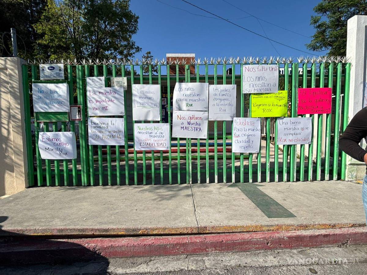 $!Carteles colocados en la reja del plantel expresan la exigencia de regreso de la maestra.